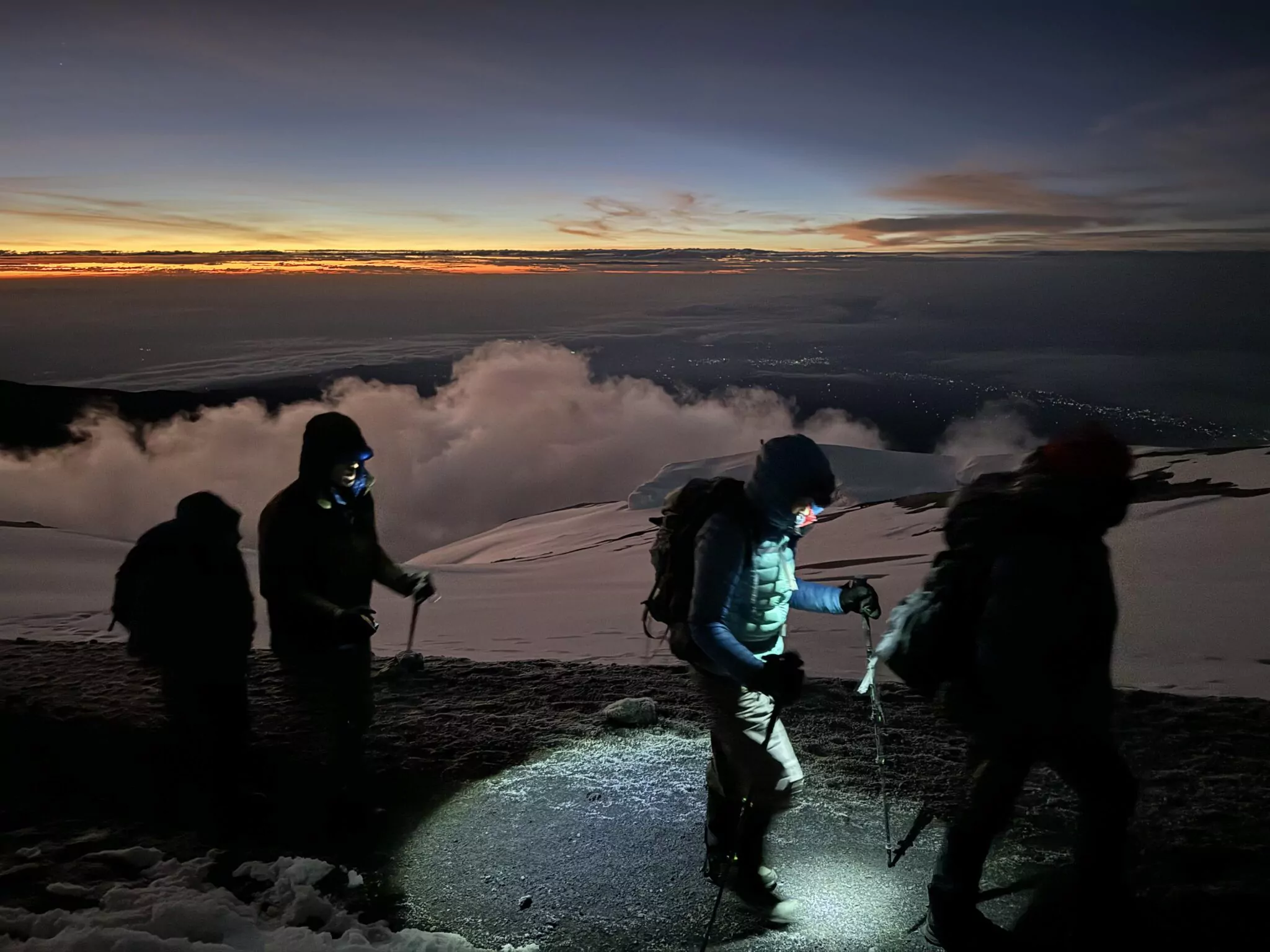 Bergsteiger mit Stirnlampen beim Sonnenaufgang in der Kilimandscharo-Gipfelzone