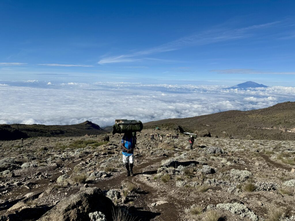 Träger mit Gepäck auf dem Kopf während einer Kilimanjaro-Besteigung