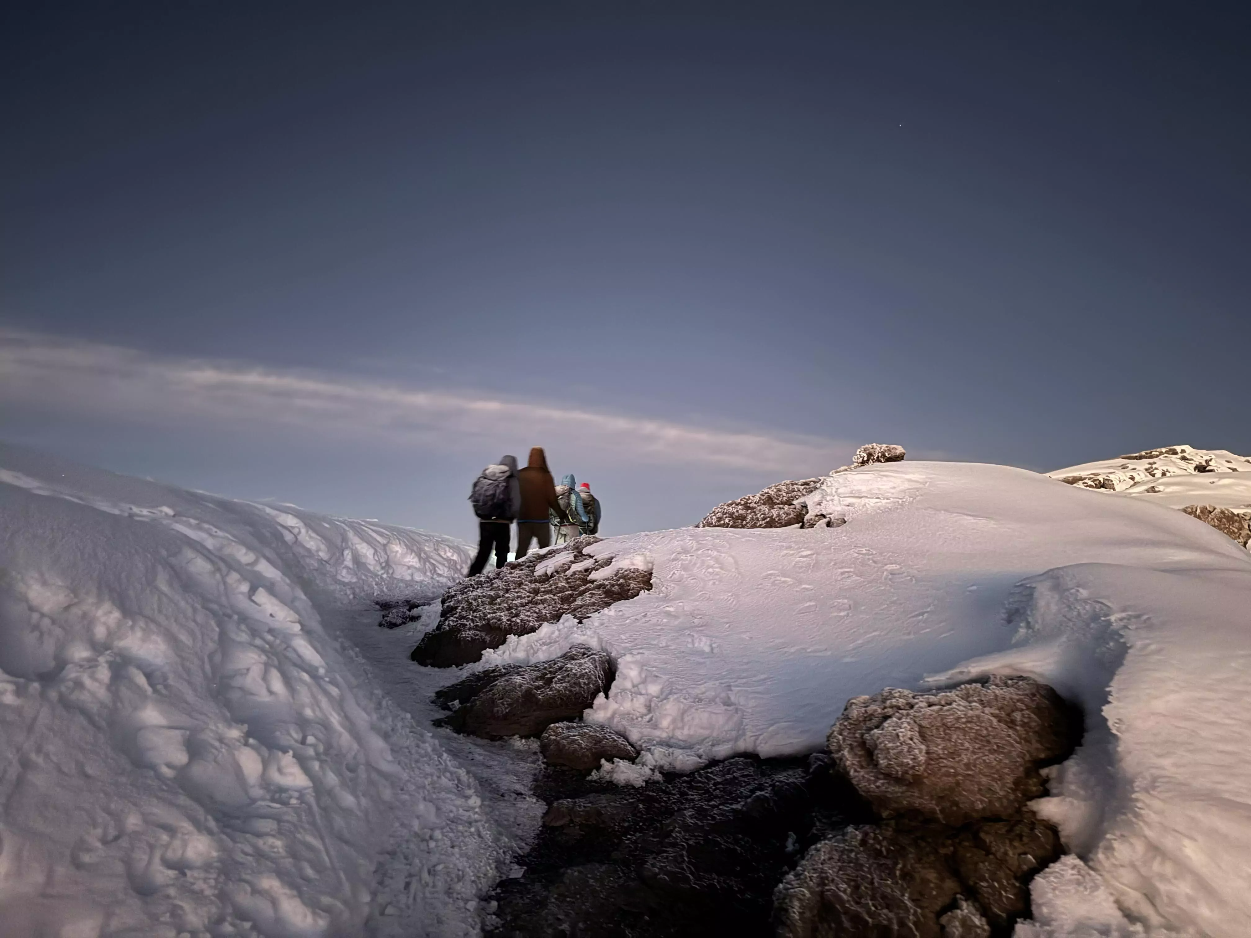 Trekker auf einem verschneiten Pfad in der Gipfelzone des Kilimandscharo