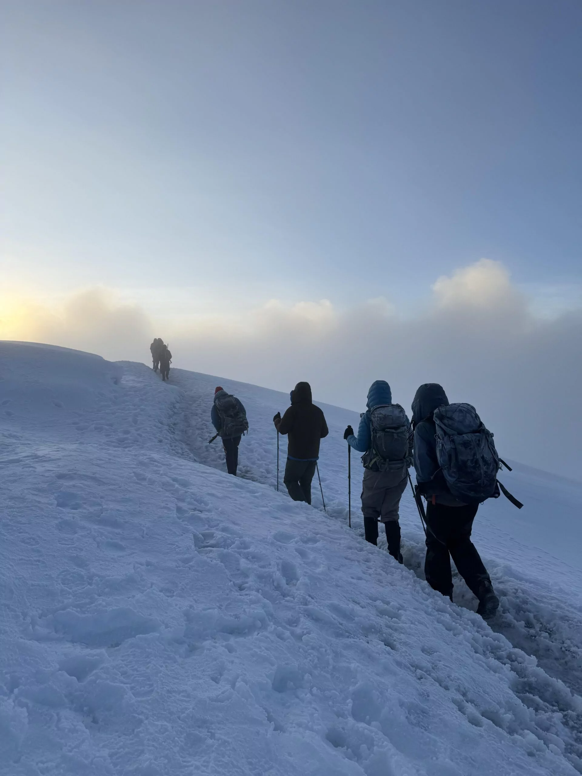 Trekker steigen langsam über den verschneiten Gipfelhang des Kilimanjaro