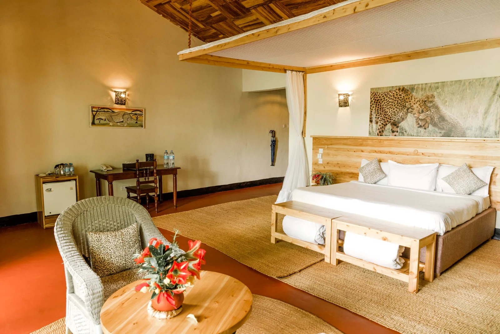 Zimmer der Olea Farm Lodge mit Doppelbett, Moskitonetz, Schreibtisch und Sitzbereich.